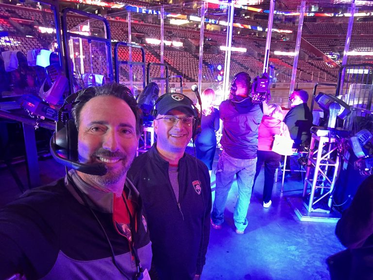 Two men at hockey game smiling at the camera