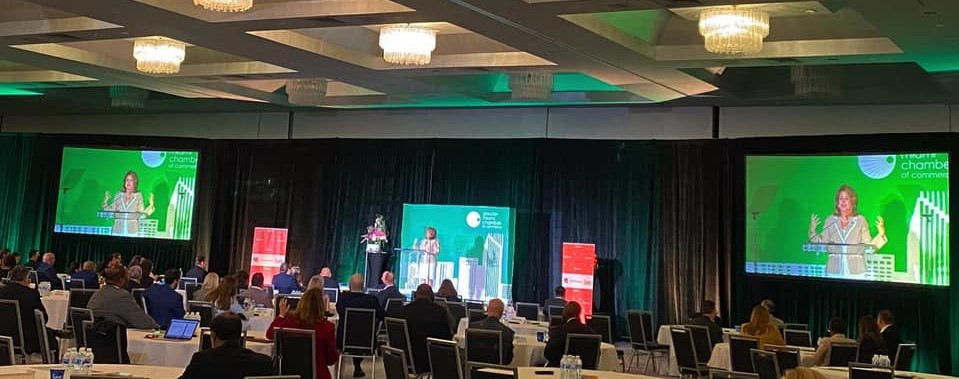Women speaking on stage and two screens at the sides