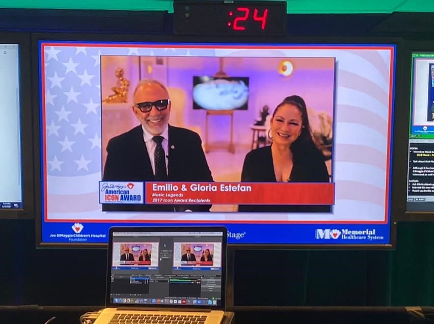 A computer and a tv with a man and woman on screen